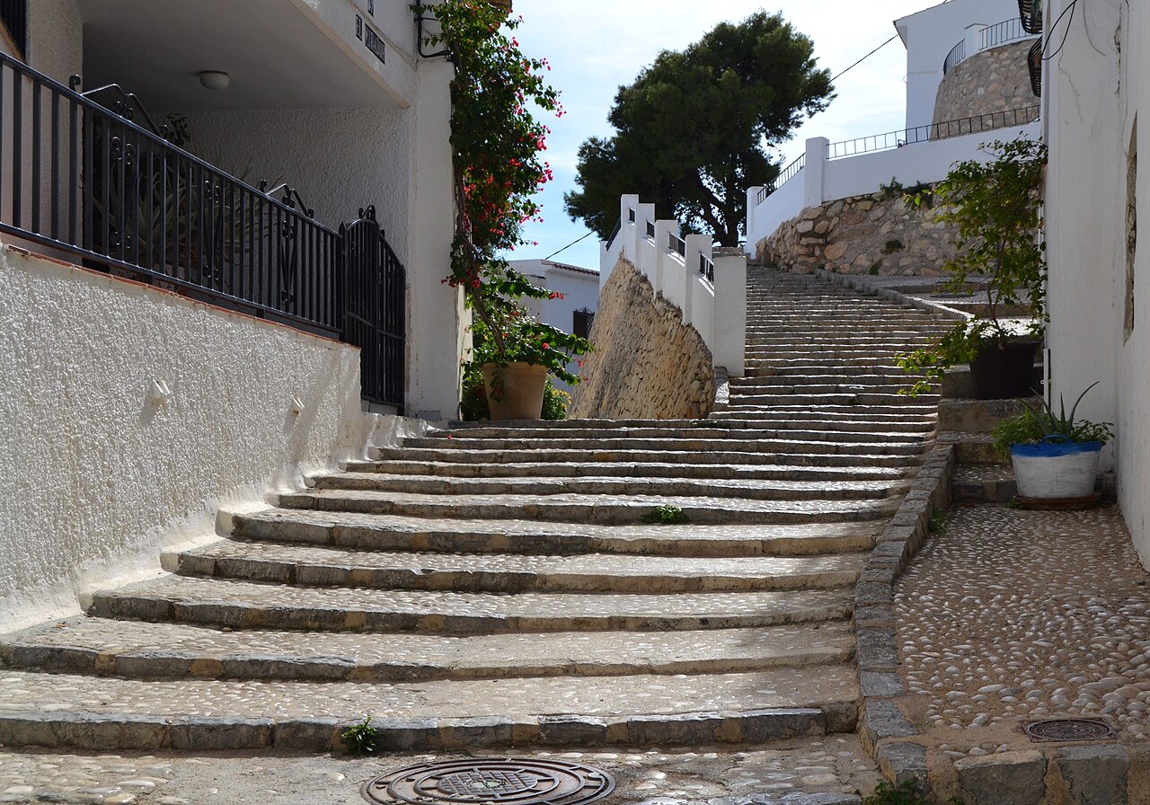 A stepped lane in the old town, whitewashed walls either side and potted plants on the landing